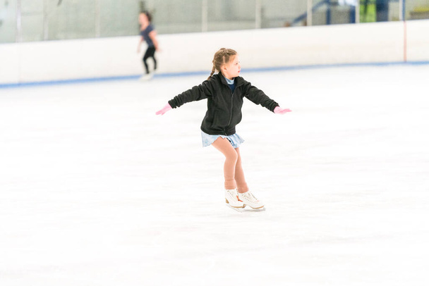 Маленька дівчинка практикує фігурне катання на ковзанах у приміщенні
. - Фото, зображення