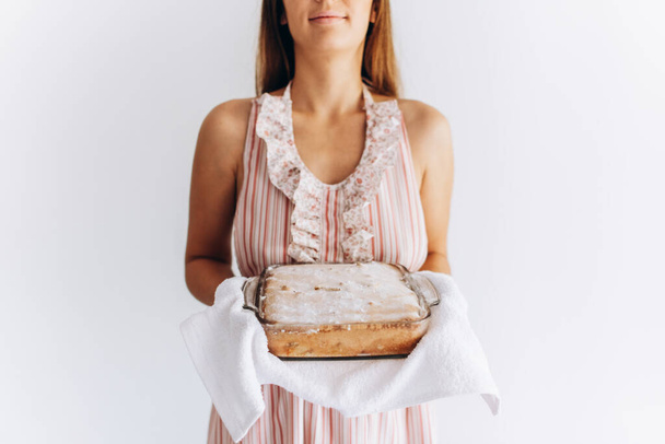 Caucasian woman is holding charlotte pie in her hands on white background close up. - Photo, Image