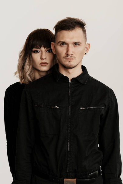 Portrait of urban fashion beautiful couple in black clothes posing over white background together. Close up fashion portrait of stylish young couple - Zdjęcie, obraz