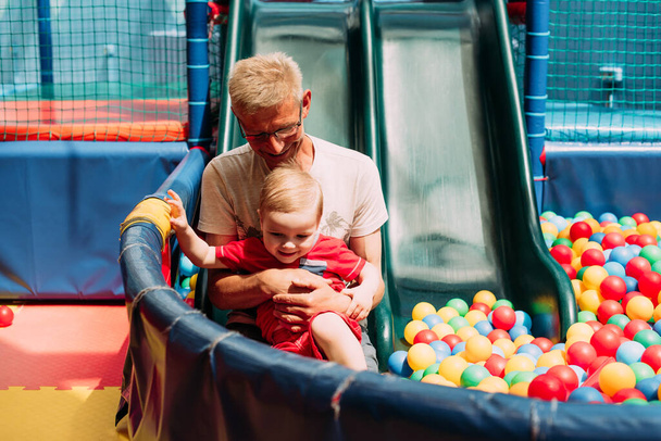 Joyeux garçon de 1 à 2 ans qui s'amuse avec son grand-père lors d'une fête d'anniversaire dans un parc d'attractions pour enfants et un centre de jeux intérieur.  - Photo, image