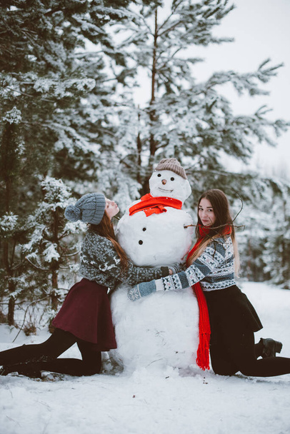 Two young teenage hipster girl friends together.Close up fashion portrait of two sisters hugs and having fun winter time,wearing sweater,best friends couple outdoors, snowy weather - Foto, Imagem