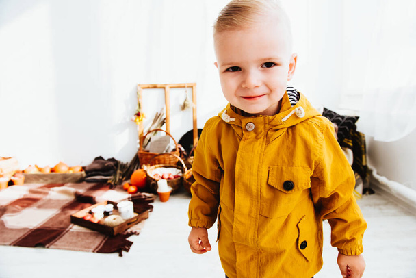Cool trendikäs hipster poika 2 vuotta vanha pukeutuu keltainen takki poseeraa koristeltu valovyöhyke syksyn sisustus kaunis kirkas syksyn lehdet. Kodikas tunnelma
 - Valokuva, kuva