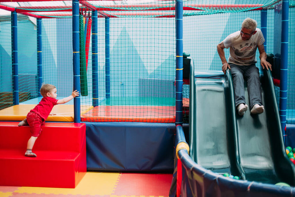Щасливий смішний хлопчик 1-2 роки розважається з дідом на вечірці в дитячому розважальному парку та ігровому центрі
.  - Фото, зображення
