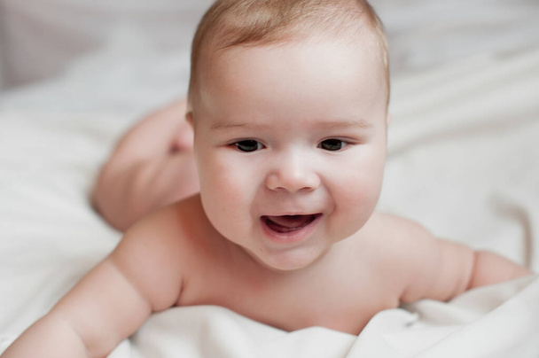白い寝具の上に寝そべっている美しい赤ん坊の男の子の柔らかい写真 - 写真・画像