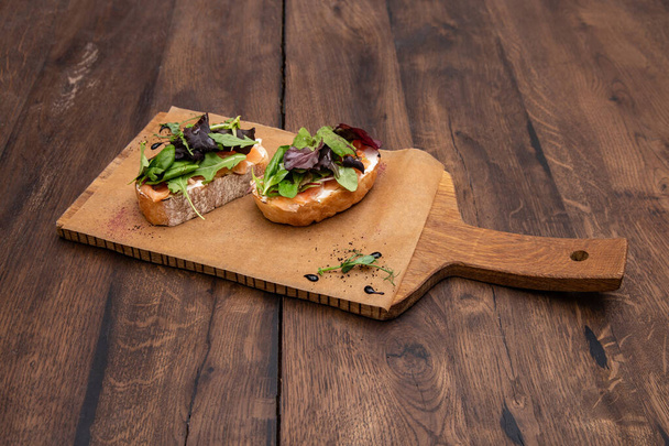 Bruschetta with salmon: Ciabatta, lightly salted salmon, cream cheese and mixed salad on a wooden Board. - Fotografie, Obrázek