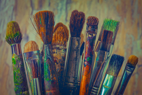 Renkli boyayla boyanmış eski fırçalar sanatçının stüdyosunda. - Fotoğraf, Görsel