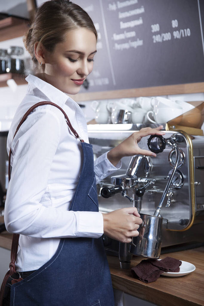  young barista girl makes coffee on a coffee machine - Valokuva, kuva