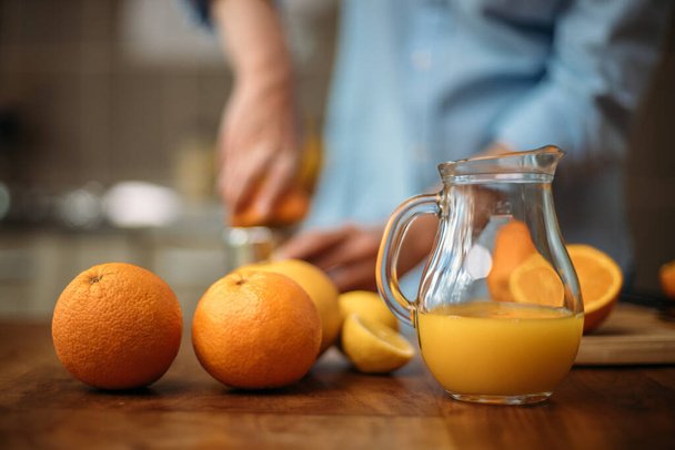 Young woman making juice from fresh oranges at home - Foto, Imagen