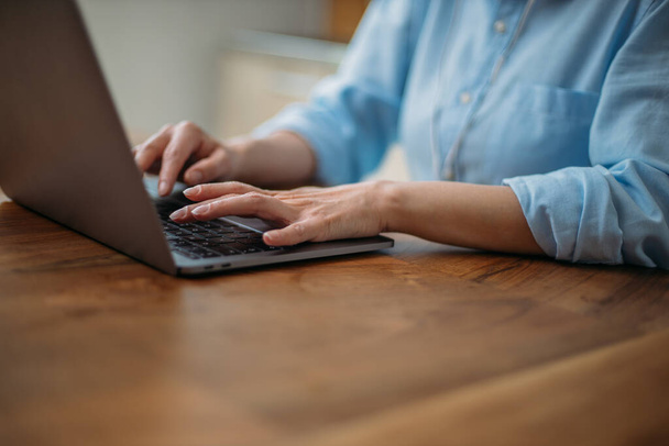 Detail van een vrouw typen op een laptop toetsenbord thuis - Foto, afbeelding