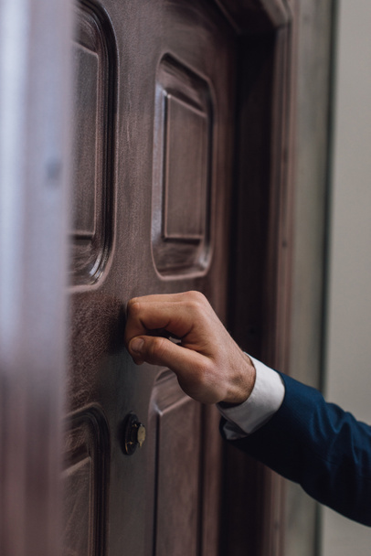 Partial view of collector knocking on door with hand - Zdjęcie, obraz