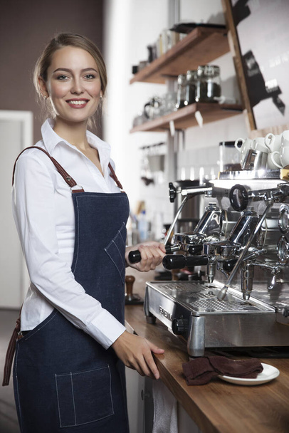  young barista girl makes coffee on a coffee machine - Valokuva, kuva
