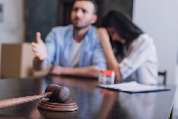 Selective focus of worried bankrupts at table with gavel in room - Foto, imagen