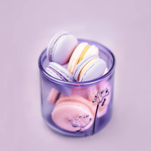 Pale purple glass with macaroons or macarons on the light gray background. Glassware made of recycled glass, eco friendly concept. Copy space - Photo, Image