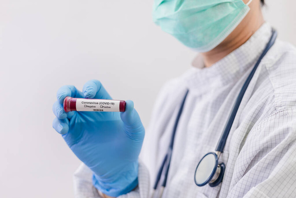 Лаборатория тестирования крови пациентов на наличие коронавируса (COVID-19) Врач держит пробирку, содержащую образец крови, который не имеет положительного или отрицательного результата на коронавирус
. - Фото, изображение