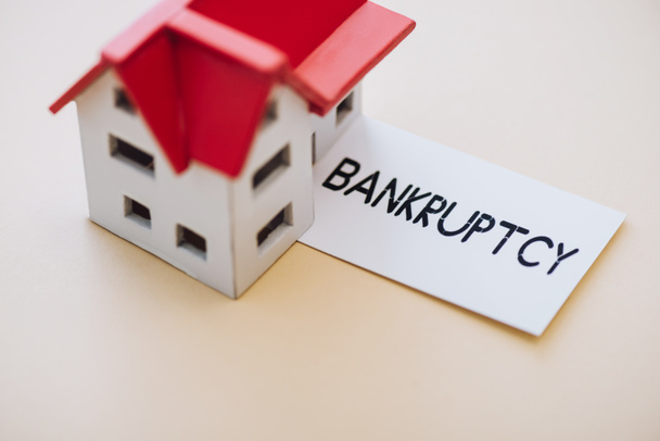 High angle view of card with bankruptcy lettering and house model on white - Foto, Imagem