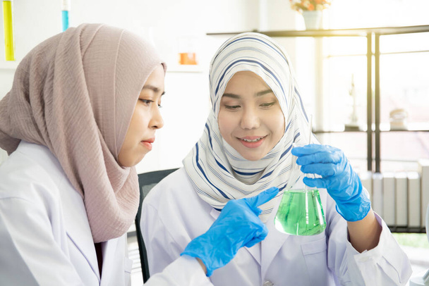 Two Muslim woman chemical scientist doing the experiment in laboratory. - Photo, image