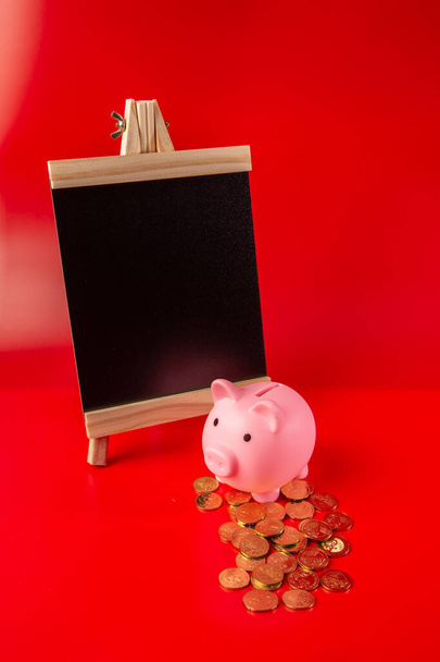 alcancía y tablero negro en blanco con moneda sobre fondo rojo - concepto de ahorro
. - Foto, imagen