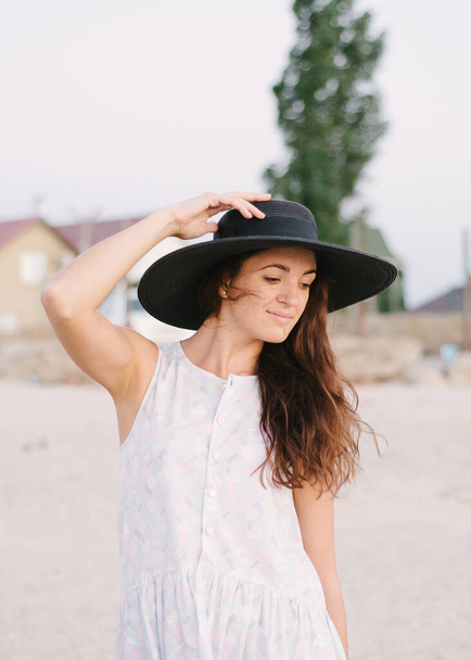 Girl in a hat walks on the beach - Фото, изображение