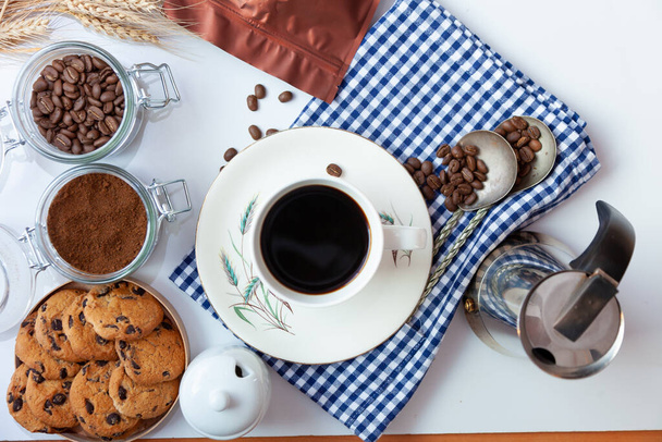 White cup of coffee and homemade round cookies with chocolate chips. Breakfast is on the table. Food at home. Still life. Coffee and coffee beans. An invigorating drink. - Foto, immagini