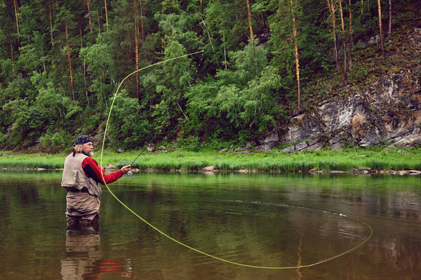 Fliegenfischer Angler macht Wurf im Wasser stehend - Foto, Bild
