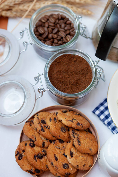 White cup of coffee and homemade round cookies with chocolate chips. Breakfast is on the table. Food at home. Still life. Coffee and coffee beans. An invigorating drink. - Φωτογραφία, εικόνα
