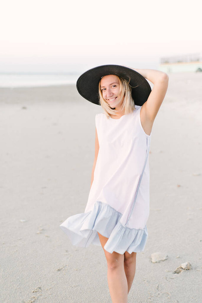 Girl in a hat walks on the beach - Φωτογραφία, εικόνα