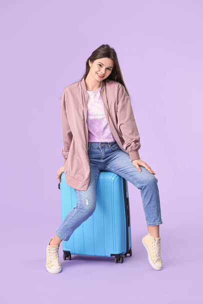 Beautiful young woman with luggage on color background - Foto, imagen