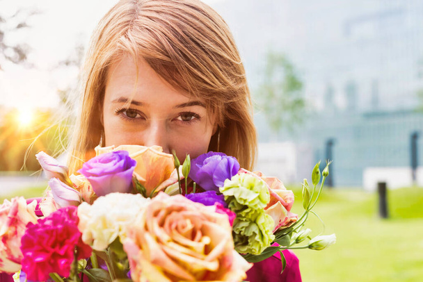 Portrait of young attractive woman holding bouquet of flowers - Foto, afbeelding