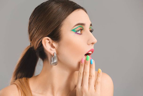 Verrast jonge vrouw met mooie manicure op grijze achtergrond - Foto, afbeelding