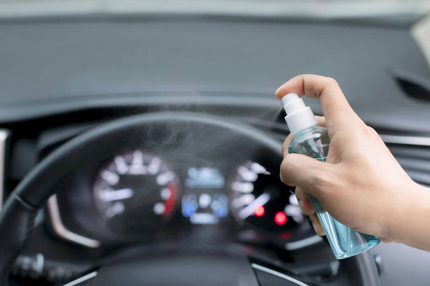 Käsi mies ruiskuttaa alkoholia, desinfiointiaine spray ohjauspyörän autossaan, estää tartunnan Covid-19 virus, saastuminen bakteereja tai bakteereja, pyyhi puhtaat pinnat, jotka ovat usein kosketuksissa
 - Valokuva, kuva