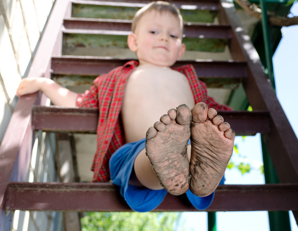 kisfiú mutatja ki a piszkos lábát - Fotó, kép