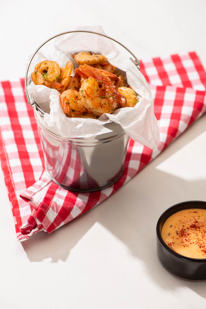 prawns on skewers on metal bucket and plaid napkin near sauce on white background - Zdjęcie, obraz