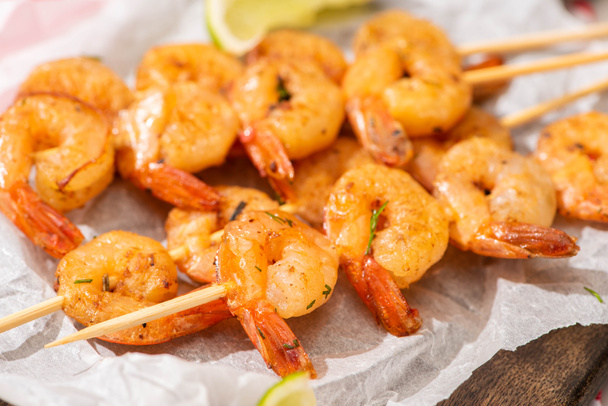 close up view of prawns on skewers with lime on parchment paper on wooden board - 写真・画像