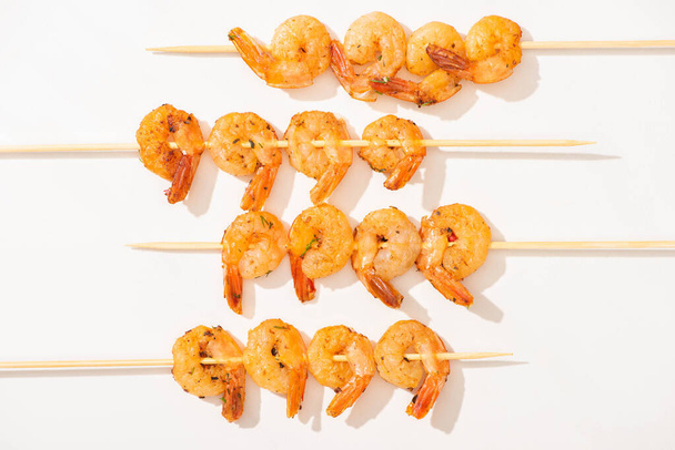 top view of prawns on skewers on white background - Foto, afbeelding