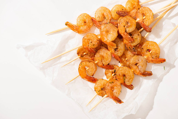 top view of prawns on skewers on parchment paper on white background - Foto, immagini