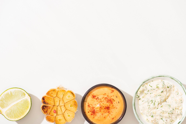 top view of garlic, lime and sauces on white background - Photo, Image