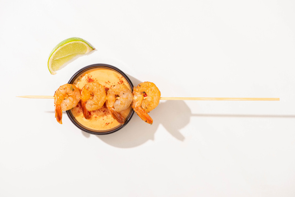 top view of delicious fried prawns on skewer with lime and sauce on white background - Photo, Image