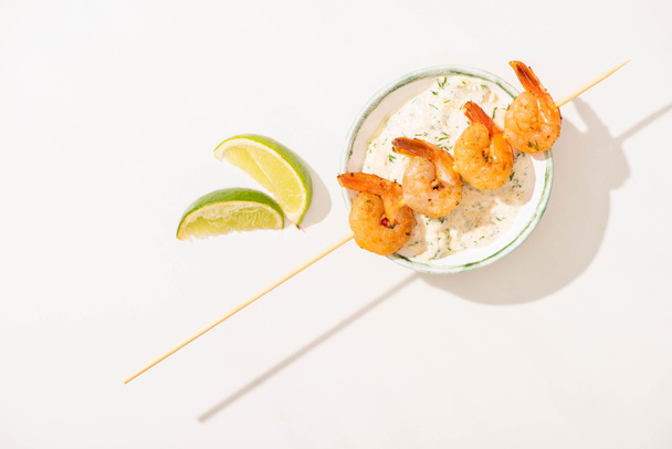 top view of delicious fried prawns on skewer with lime and sauce on white background - Photo, image