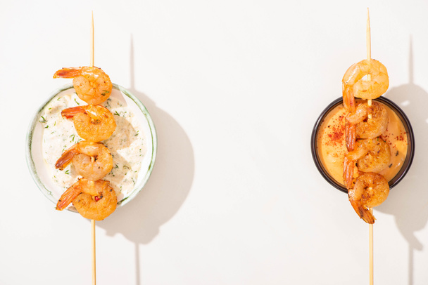 top view of delicious fried prawns on skewers with sauces on white background - Photo, Image