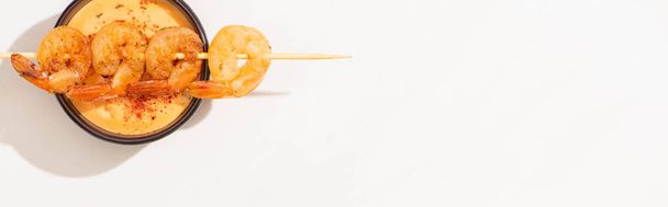 Draufsicht auf köstliche gebratene Garnelen am Spieß mit Sauce auf weißem Hintergrund, Panoramaaufnahme - Foto, Bild