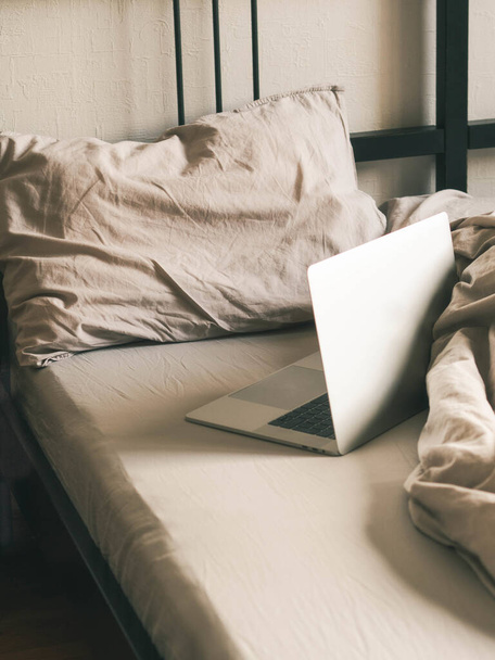 Laptop op het bed in de slaapkamer. Werk vanuit huis of een comfortabel tijdverdrijf online. - Foto, afbeelding