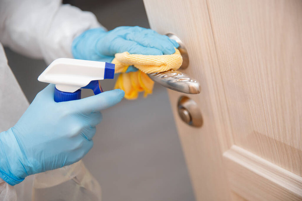Disinfection and cleaning door handles of house from infection with virus and microbes in biochemical suit. Coronavirus protection concept - Photo, Image