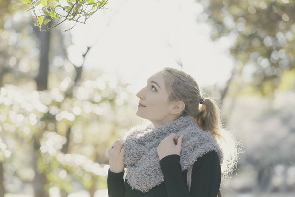 Güneş ışığı parkında nazik bir ifadeyle genç beyaz bir kadın. - Fotoğraf, Görsel