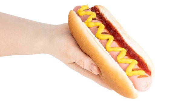 Kézzel tartott hot dog mustárral elszigetelt fehér háttérrel. Vágási útvonal. - Fotó, kép