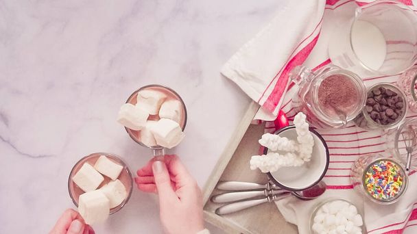 Flat lay. Making Amrican hot chocolate in glass cup with jumbo marshmallows. - Photo, Image