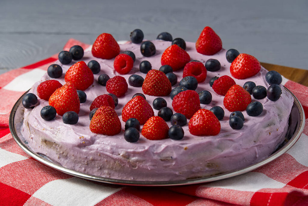 Zelfgemaakte Cheesecake met bessen. Cheesecake met aardbeien, bosbessen en frambozen op grijze houten ondergrond - Foto, afbeelding