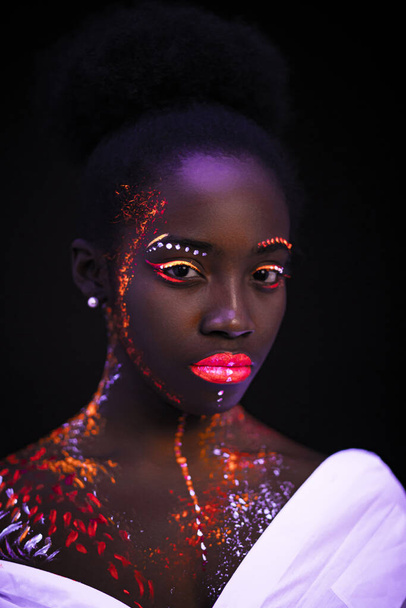 african model in neon light, girl with fluorescent makeup - Foto, afbeelding