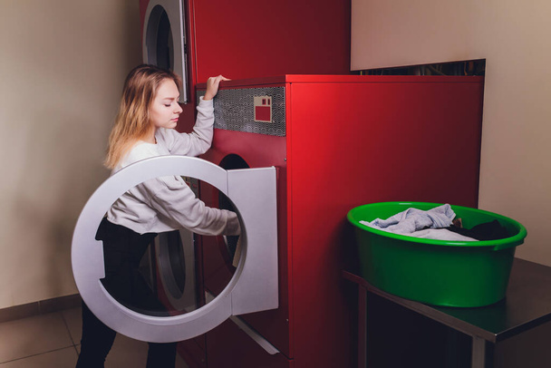 Young woman pressing buttons on washing machine in dry-cleaning. - Valokuva, kuva