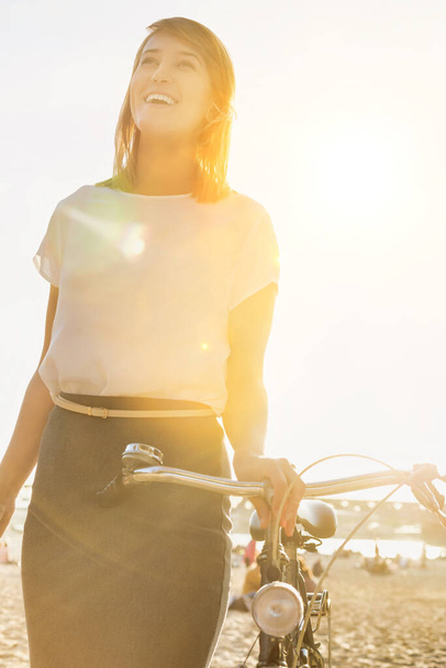 Portrait de jeune femme d'affaires séduisante tenant un vélo tout en marchant sur la plage
 - Photo, image