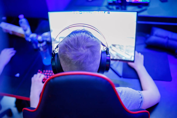 Professional cyber gamer studio room with personal computer armchair, keyboard for stream in neon color blur background. Soft focus - Photo, image